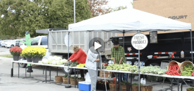 A woman stands at a farmers market stand
