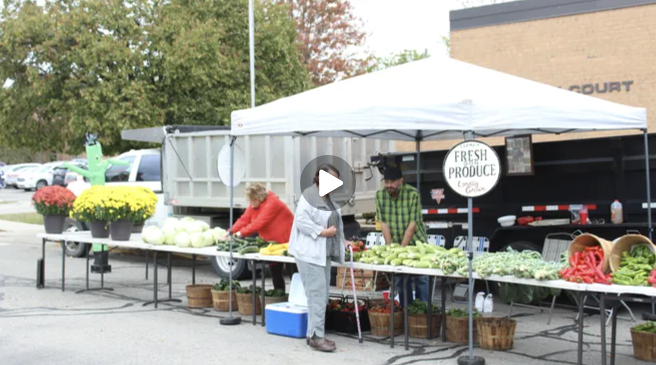 A woman stands at a farmers market stand