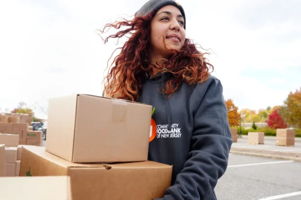 A woman carries boxes of food towards her local foodbank