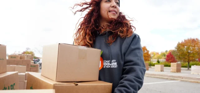 A woman carries boxes of food towards her local foodbank