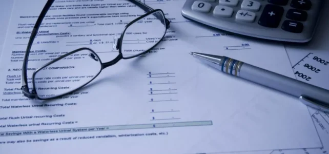 As open enrollment begins, Arizonans see skyrocketing costs for ACA health plans Glasses, a pen and a calculator strewn across bills