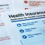 Pen resting on health insurance application forms