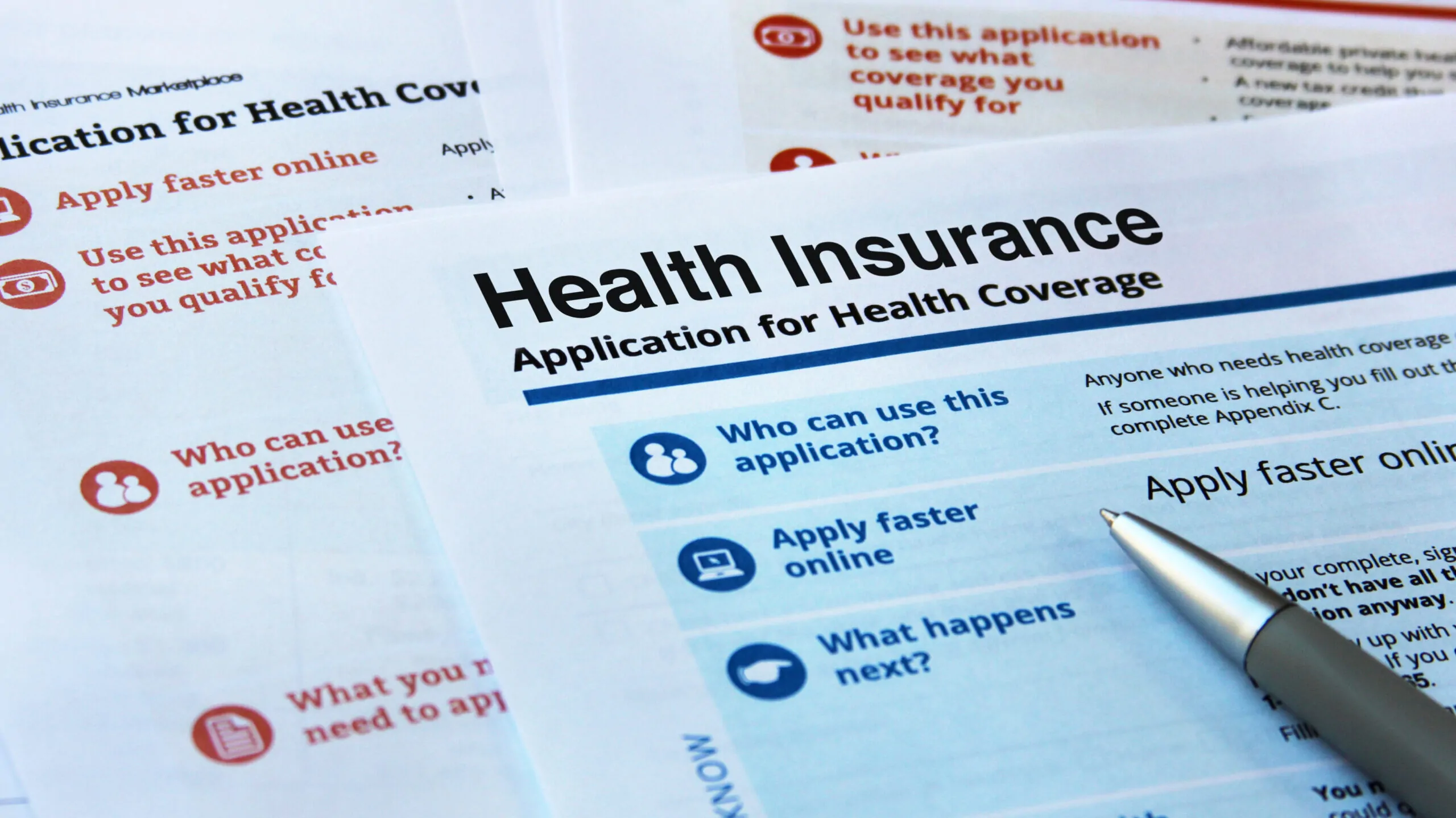 Pen resting on health insurance application forms