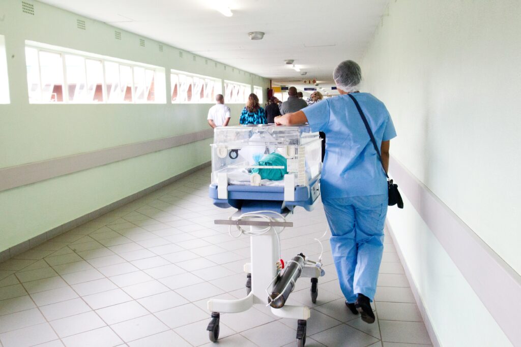 A nurse rolls down a cradle in the hallway. 