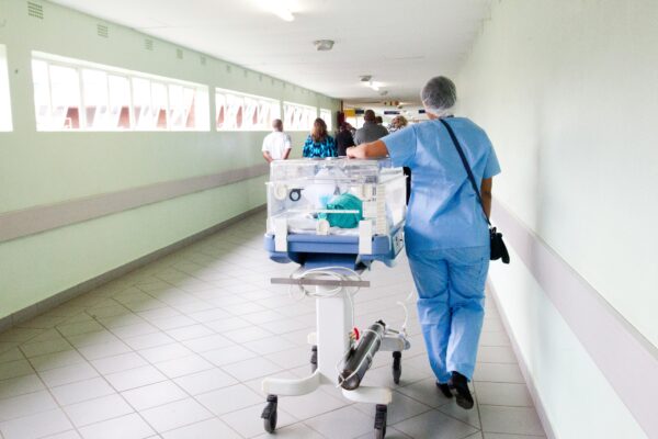 A nurse rolls a cradle down the hallway