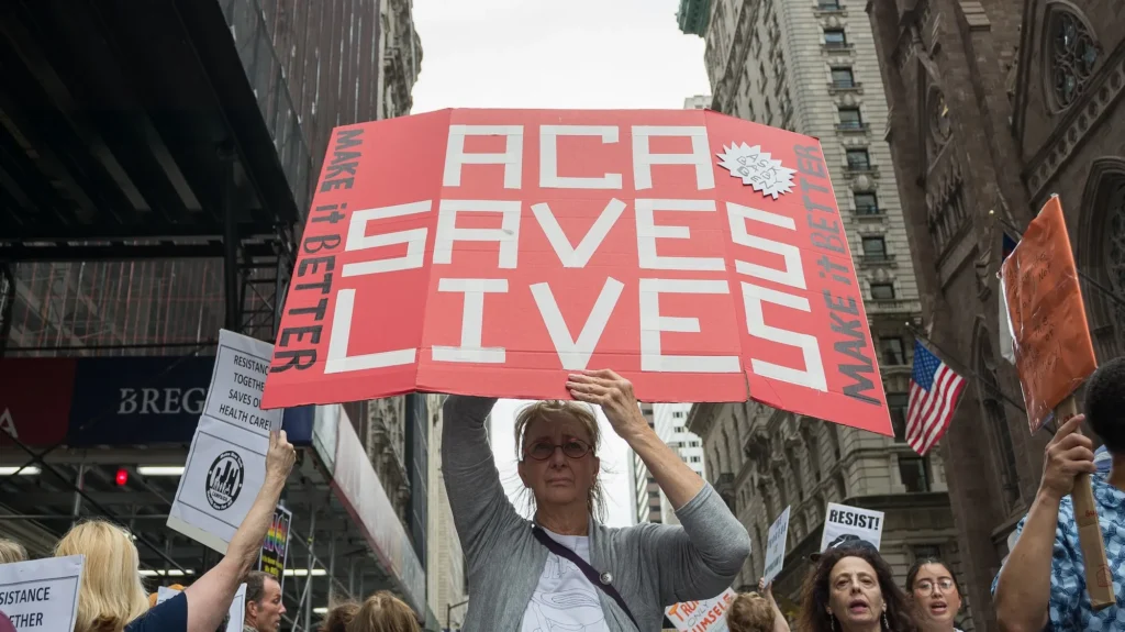 A woman holding a protest sign that says "ACA Saves Lives" - Albin Lohr-Jones/Pacific Press/Zuma