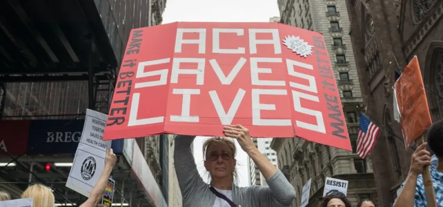 A woman holding a protest sign that says "ACA Saves Lives" - Albin Lohr-Jones/Pacific Press/Zuma