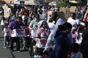 People in need line up to receive free food during a 2025 Thanksgiving food giveaway in Oakland, California. Tens of thousands of Bay Area households turned to emergency groceries after a temporary halt in SNAP benefits worsened already high levels of food insecurity. (Photo credit: Justin Sullivan/Getty Images)